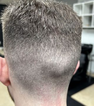 A close-up of a man with a shaved head, showcasing a clean and stylish haircut.